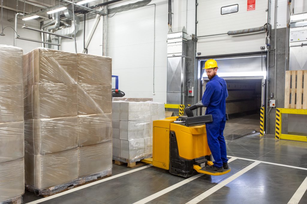 Young,Forklift,Driver,Loading,Goods,In,A,Warehouse,With,Gate