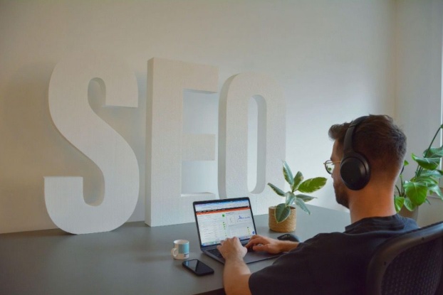 SEO specialist wearing headphones while working on a laptop in a modern office