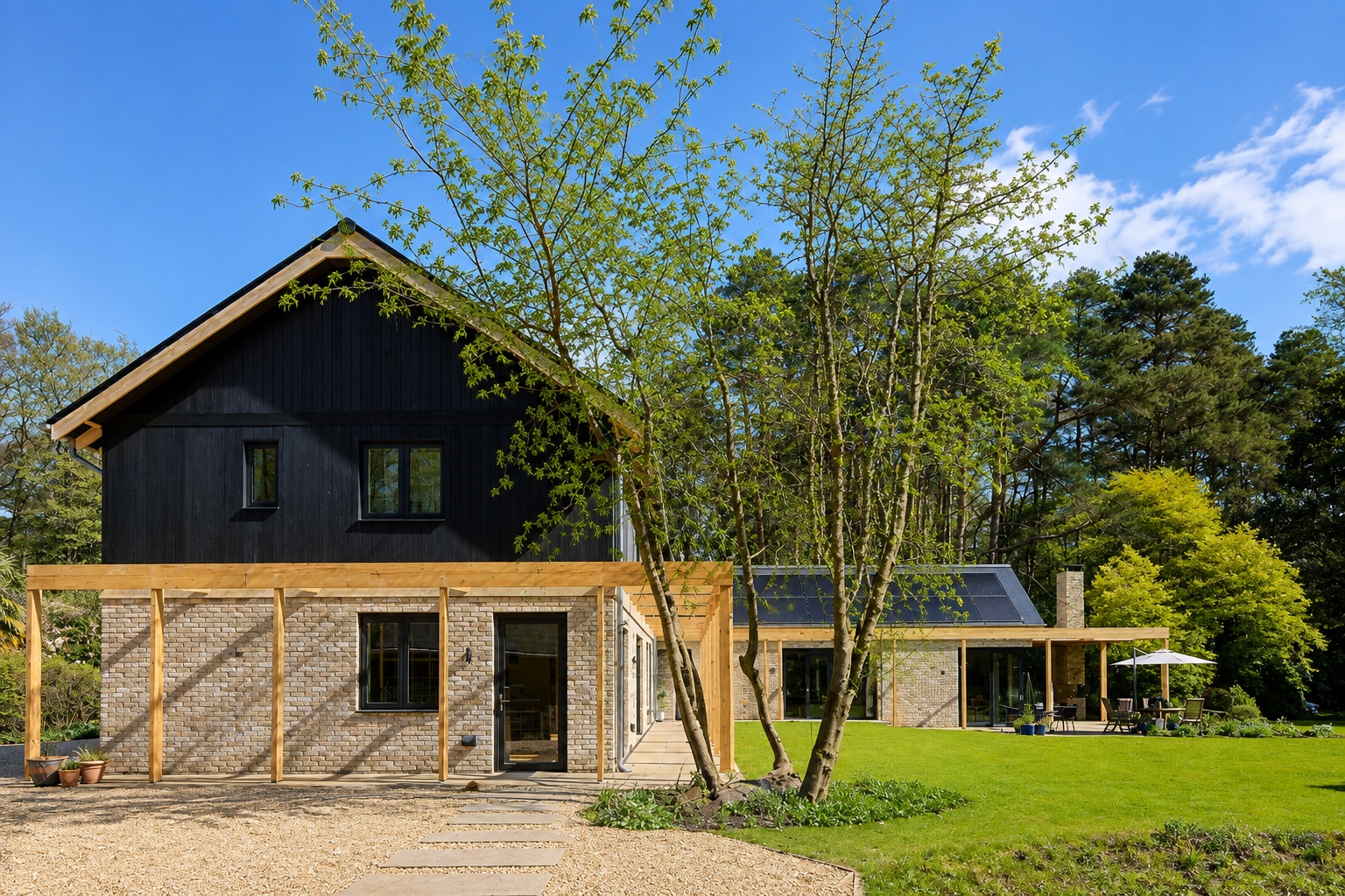 Modern UK home with triple glazed windows, dark timber cladding, brick walls and landscaped garden